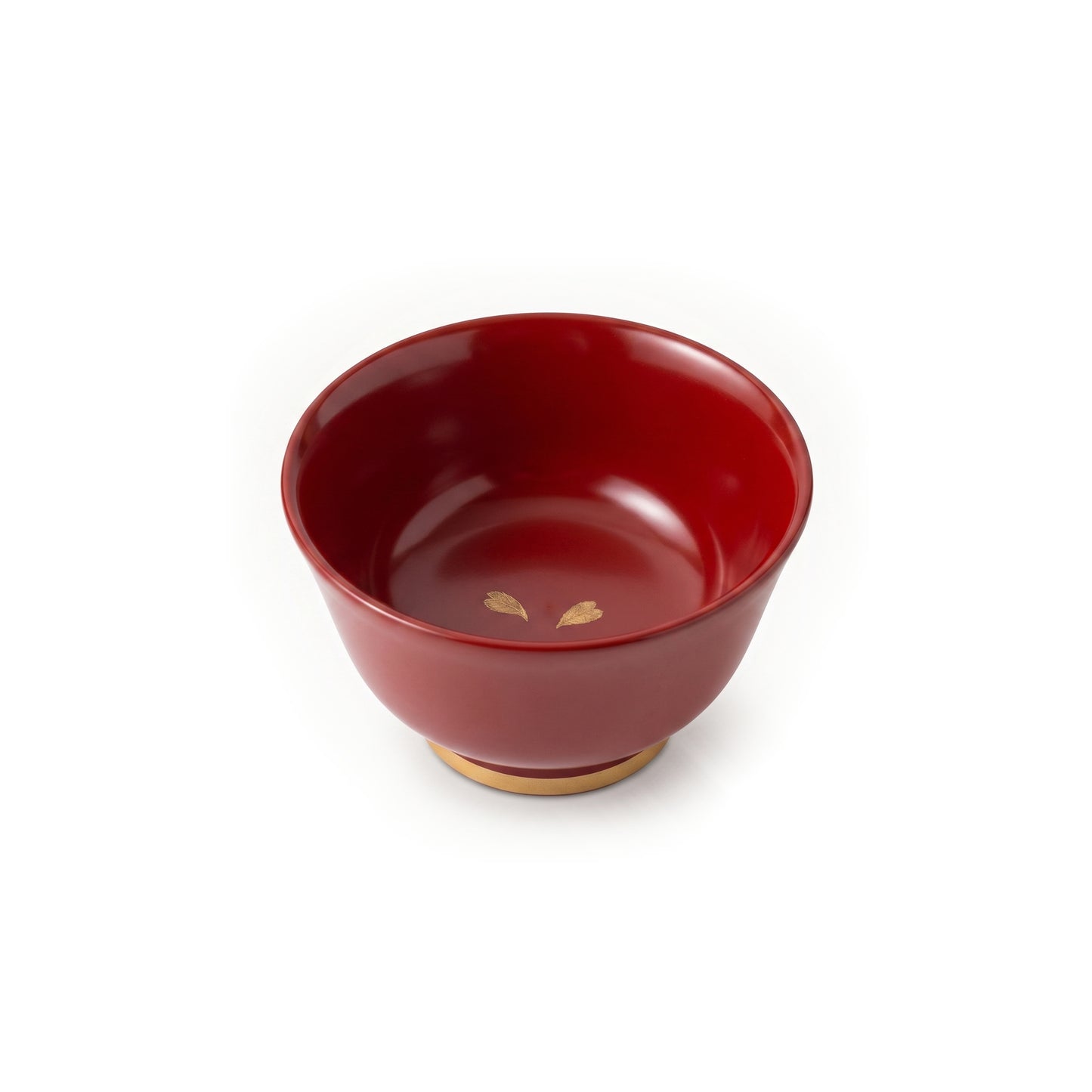 A single red lacquer cup from above, its glossy red interior holding two gold cherry blossom petals near the base's centre.