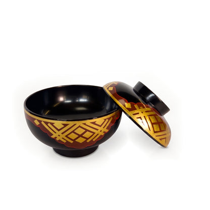 The open bowl from a higher angle, black interior in view, with the patterned lid resting against its right side.