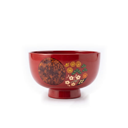 A single red soup bowl on a raised foot, its mottled copper circle beside chrysanthemum, pine, and plum blossom motifs.