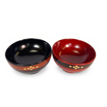 The black and red lacquer bowls seen from above, showing the black interior of one and dark red interior of the other.