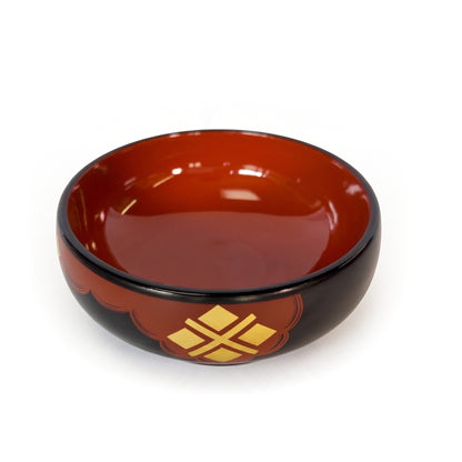 A single bowl tilted to show its deep red interior, the gold four-diamond cross sitting left of centre on a red cloud patch.