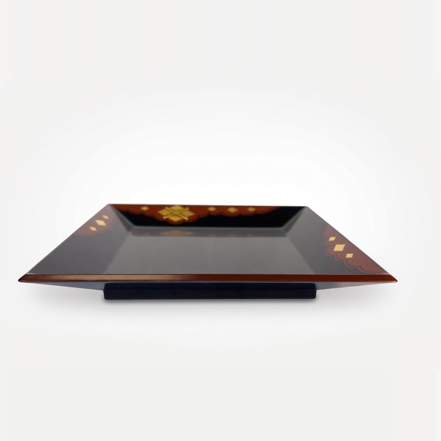 Low-angle view of the whole tray, showing the rim's thickness and curve, resting on a black stand beneath its red-brown edge.