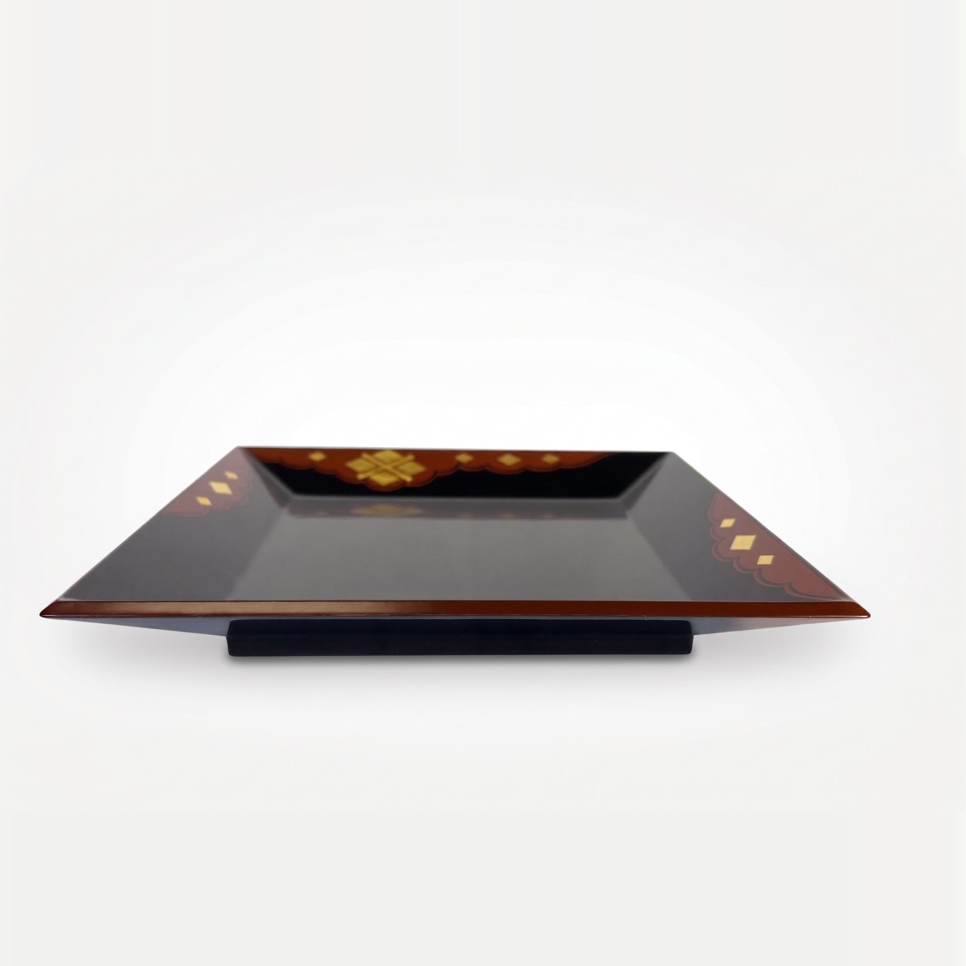 Low-angle view of the whole tray, showing the rim's thickness and curve, resting on a black stand beneath its red-brown edge.