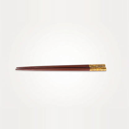 Viewed alone, the deep red lacquer pair runs the full length from a fine tip to its gold-leaf grip end.