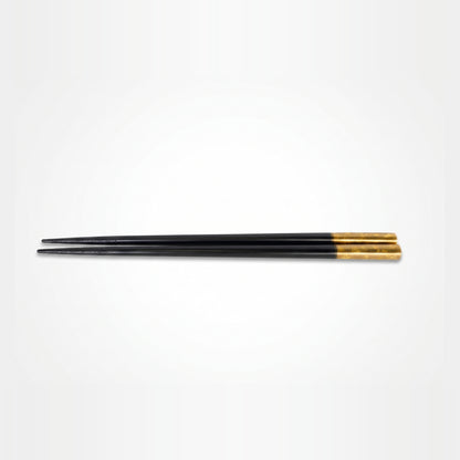 A single pair finished entirely in black lacquer, tapering from a fine tip to a mottled gold-leaf grip end.