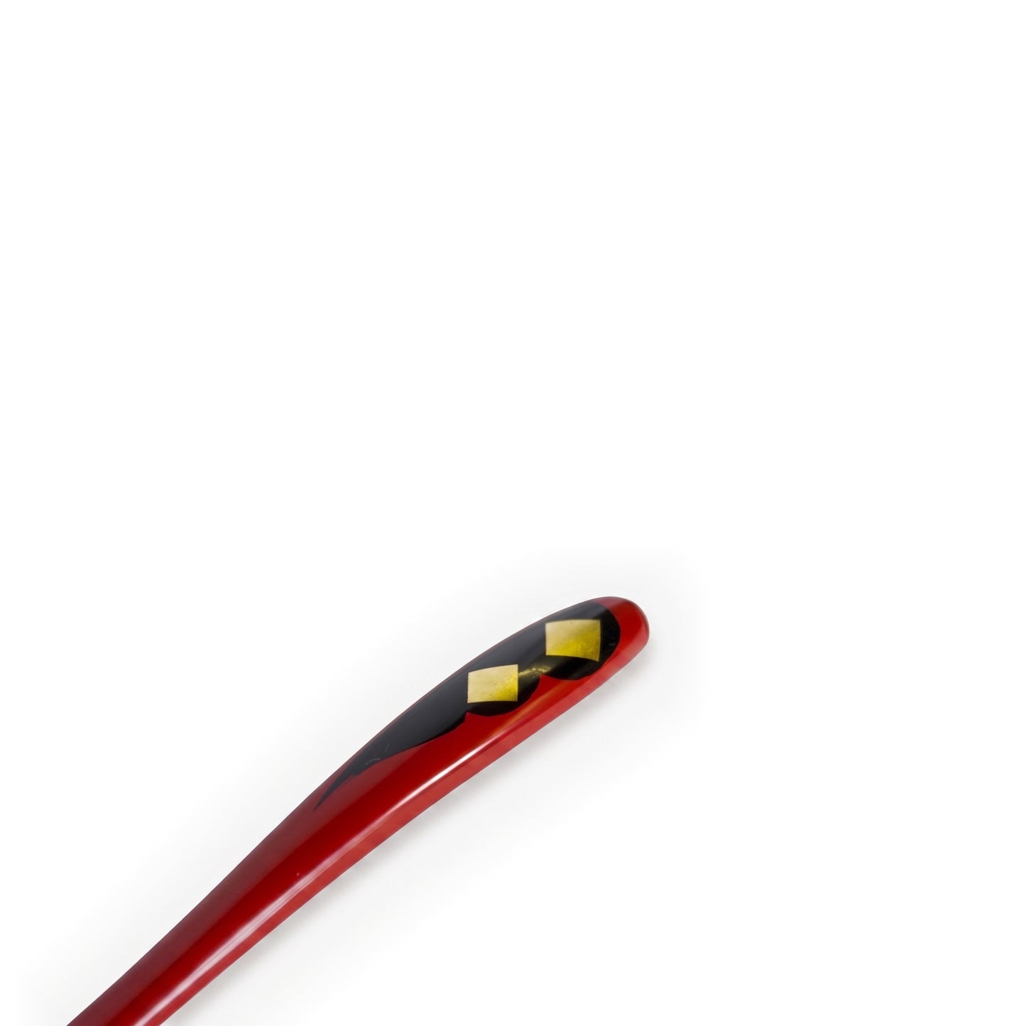 Close view of the red handle tip, where two gold diamonds, the smaller below the larger, sit on a black cloud shape.