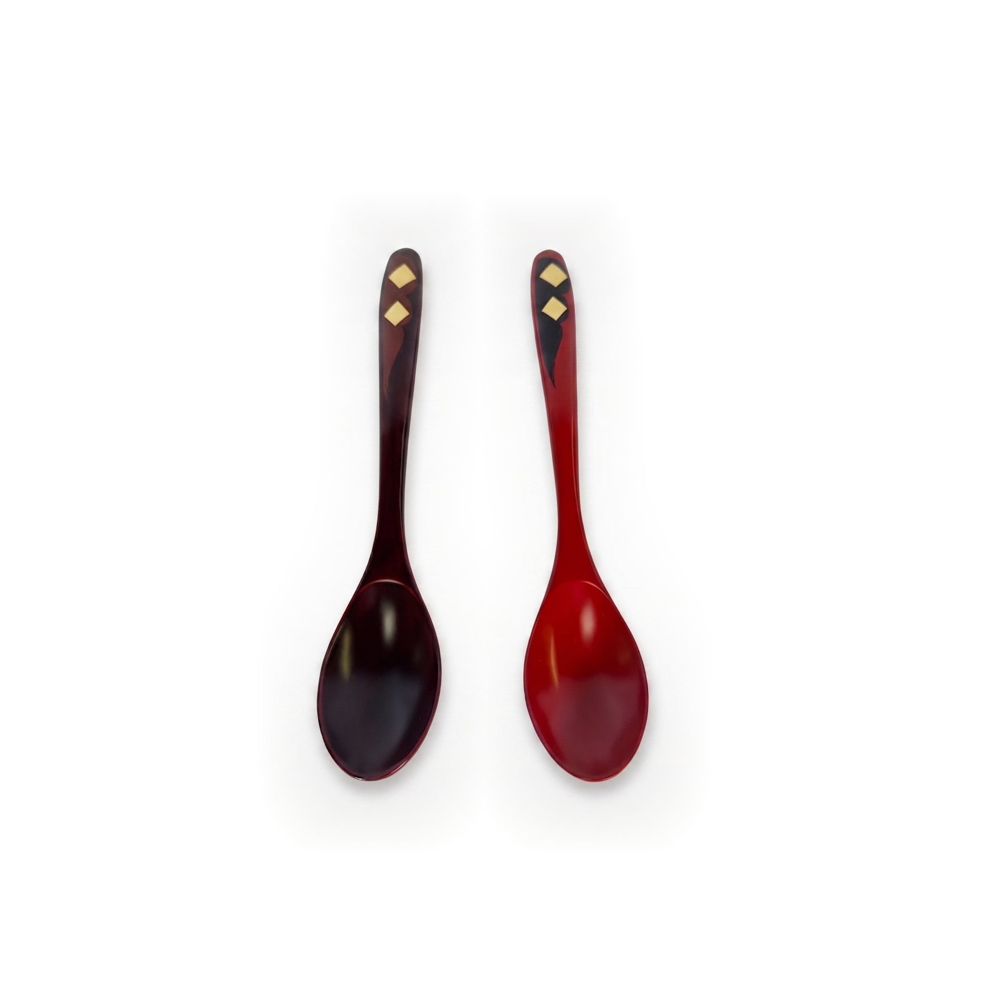 The pair stood upright side by side, bowls at the base, maroon spoon left and red right, gold diamonds near the handle tips.