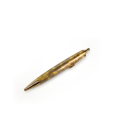 The pen alone on a diagonal, tip at the lower left, gold leaf and pale amber facets running along the barrel.